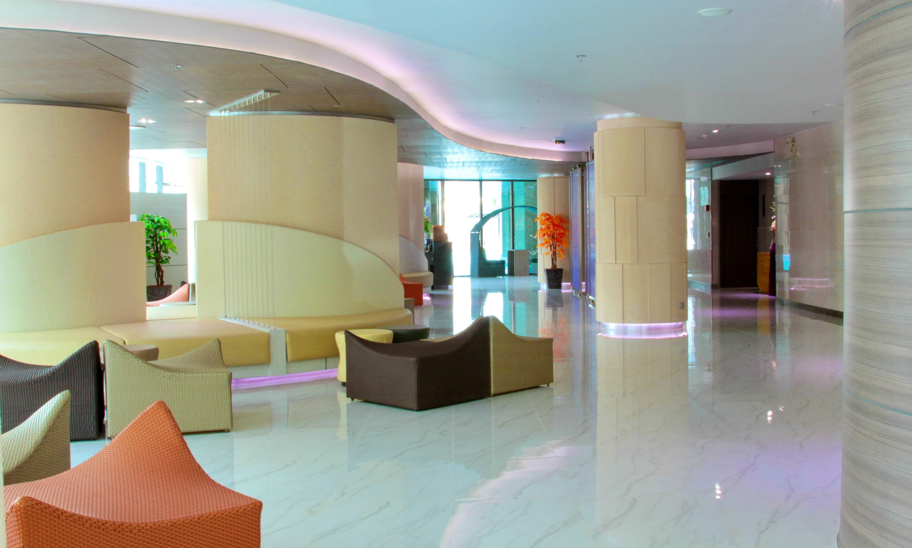 A spacious lobby with a curved seating area, large pillars, and a polished floor.