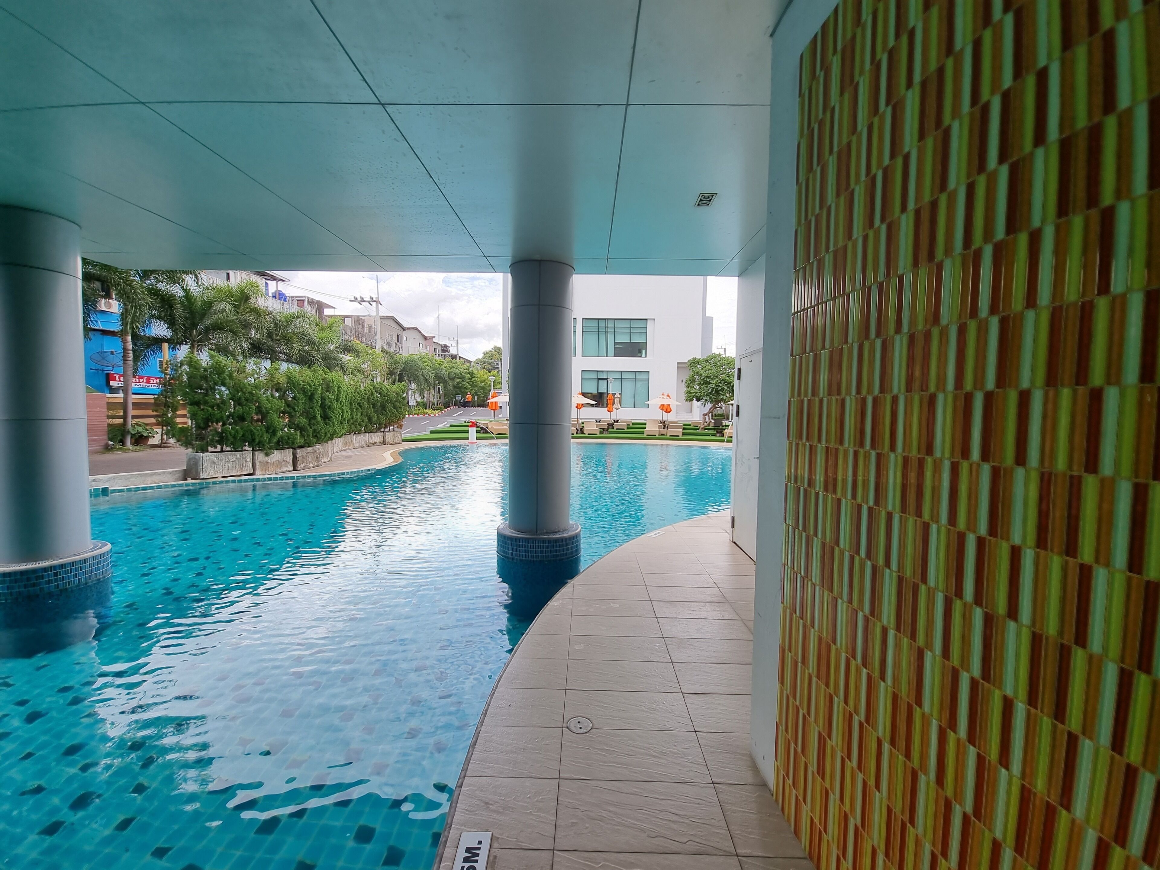 An indoor swimming pool with clear blue water, surrounded by tiled walls and pillars.