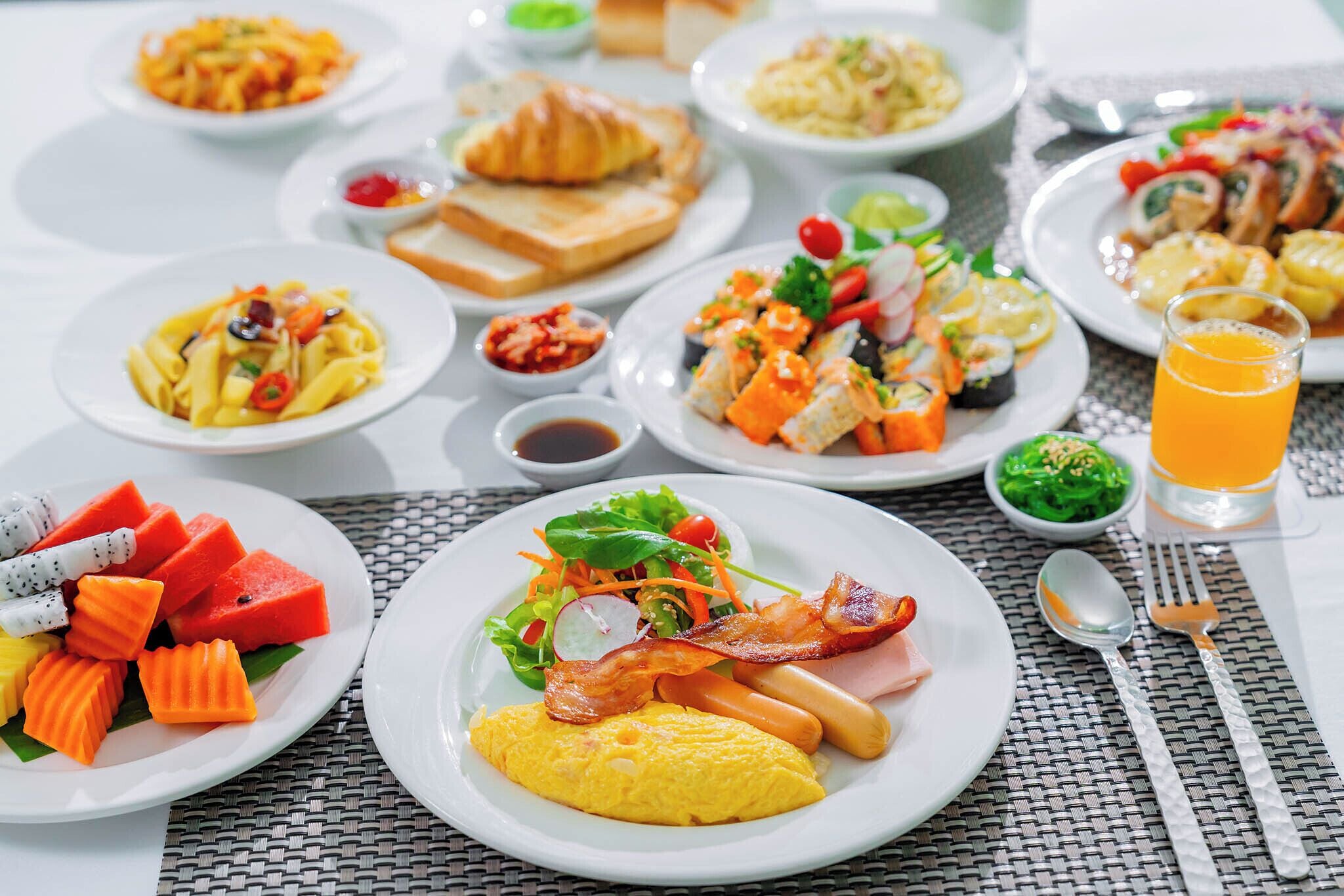 A variety of breakfast dishes on plates, including eggs, bacon, and vegetables.