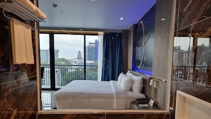 Habitación de hotel moderna con una cama grande, una bañera y vistas a la ciudad desde la ventana.