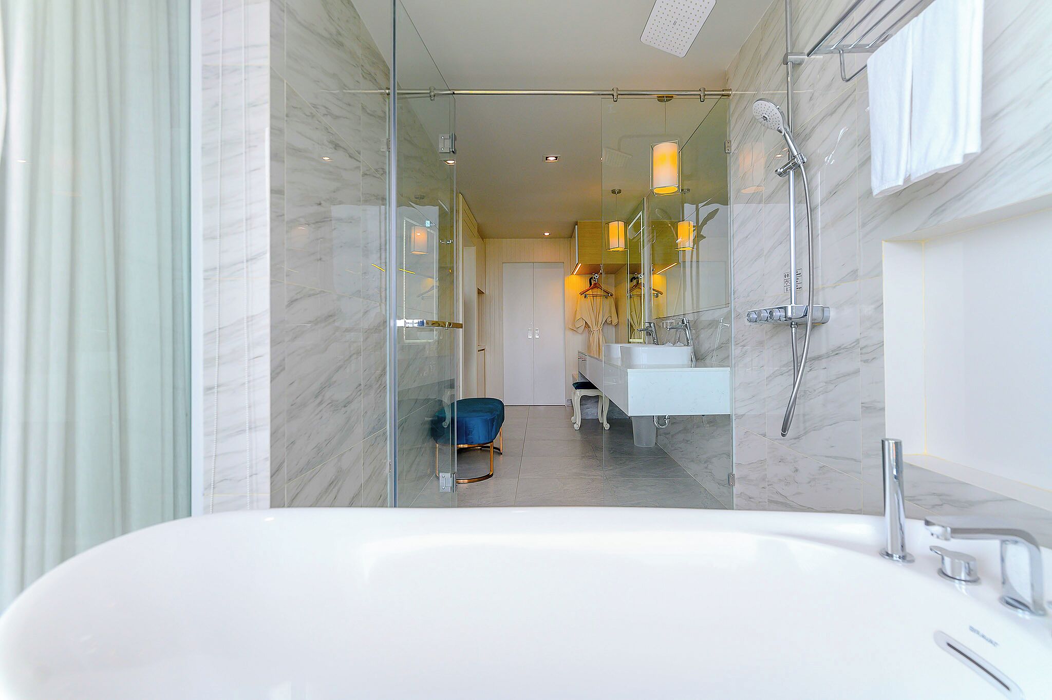 A modern bathroom with a glass-enclosed shower, a white bathtub, and a vanity with a mirror.