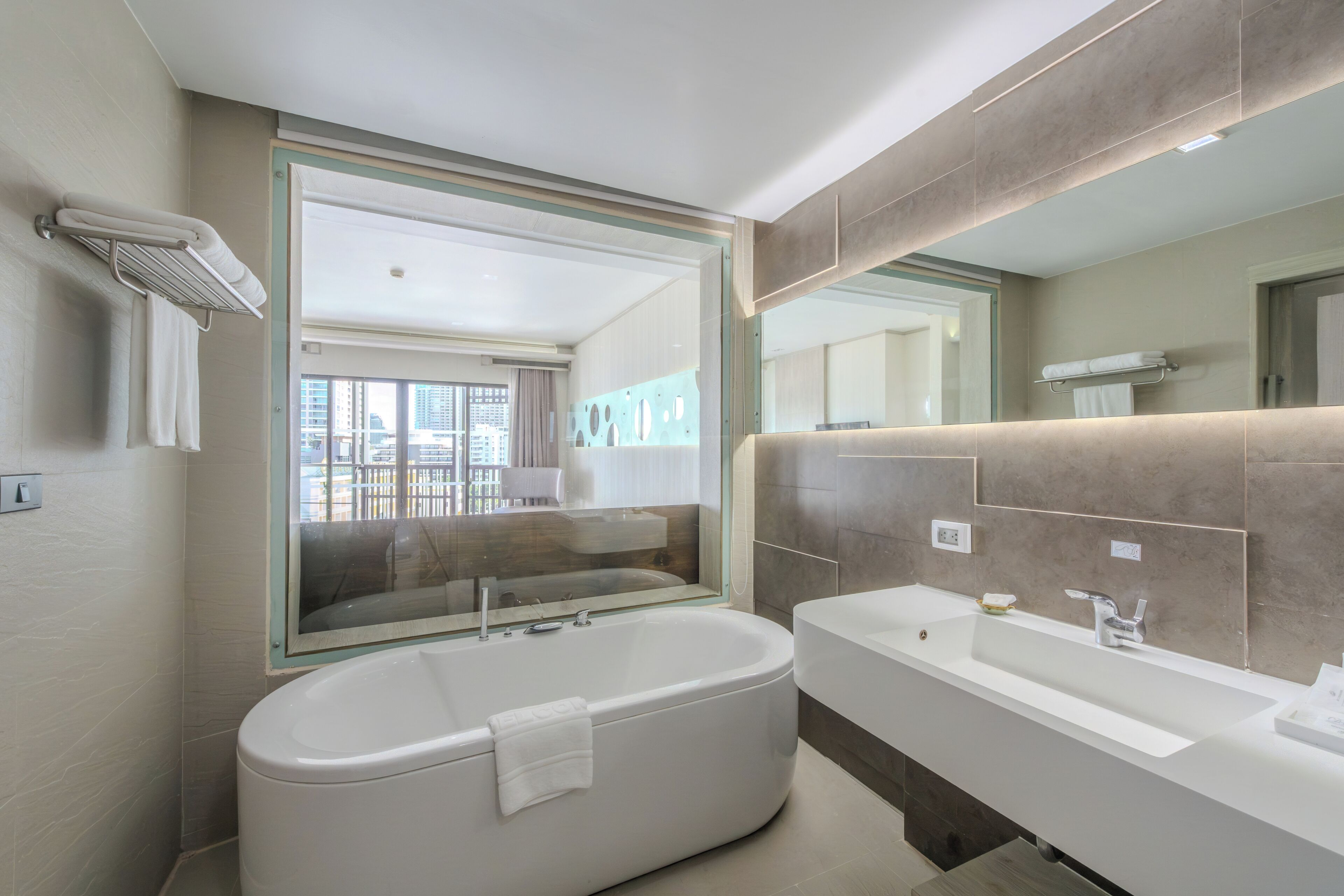 Une salle de bain moderne avec une baignoire, un grand miroir et un meuble-lavabo.