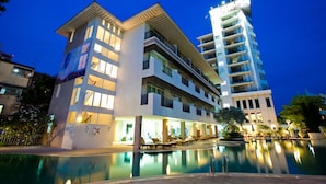 Un hotel moderno con piscina, varios balcones y una fachada bien iluminada.