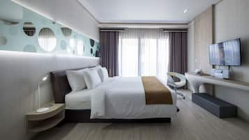 Quarto de hotel moderno com uma cama grande, televisão, secretária e um design de parede único.