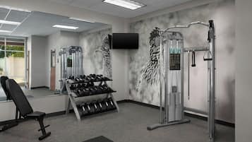 A gym with weightlifting equipment, dumbbells, and a TV on the wall.