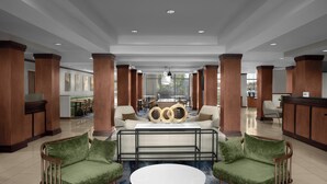 A spacious lobby with a central seating area, a reception desk, and a view of the outdoors.