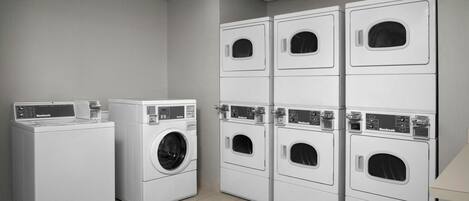 A laundry facility with multiple rows of white front-loading washers and dryers.