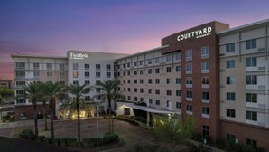 A multi-story hotel with a courtyard, Marriott branding, and a parking area with palm trees.
