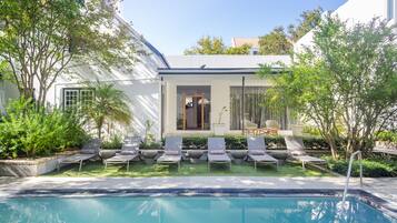 Una piscina al aire libre, sombrillas, sillones reclinables de piscina