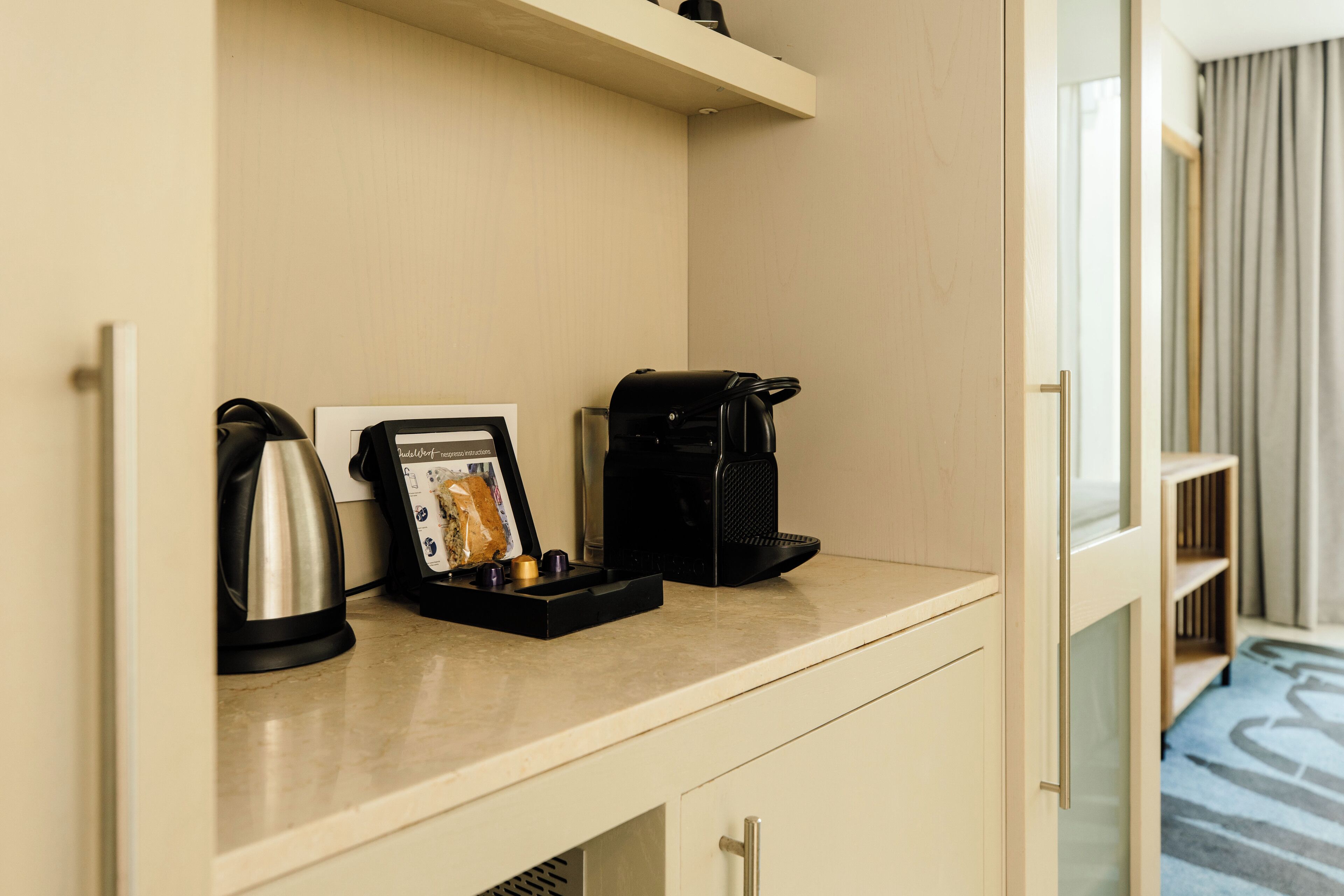 Una kitchenette de hotel con cafetera, hervidor de agua y una foto enmarcada sobre la encimera.