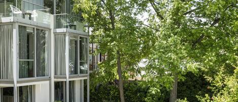 Un edificio moderno con piscina, rodeado de exuberante vegetación y árboles.