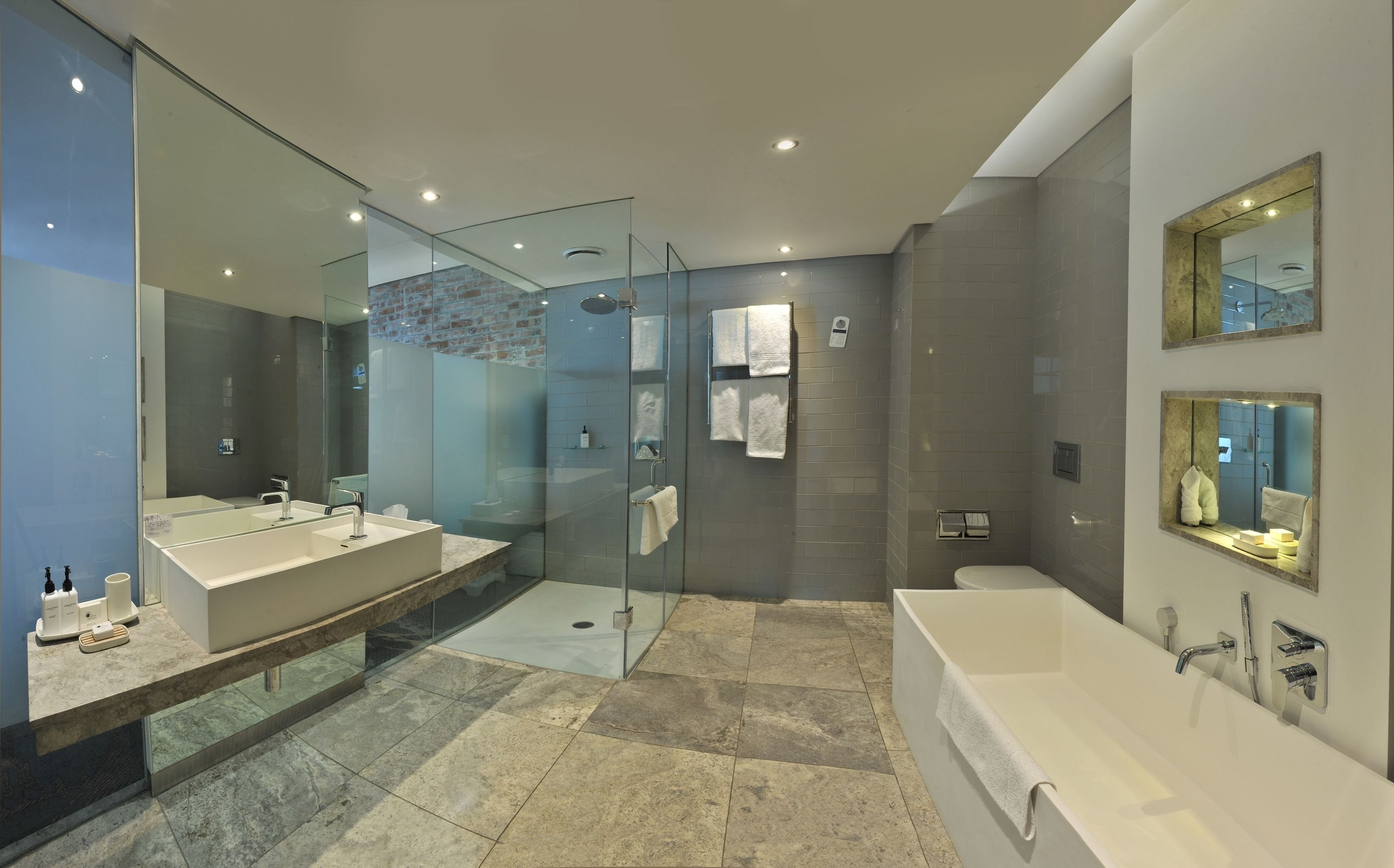 Un baño moderno con ducha de vidrio, una bañera grande y un tocador con lavamanos doble.