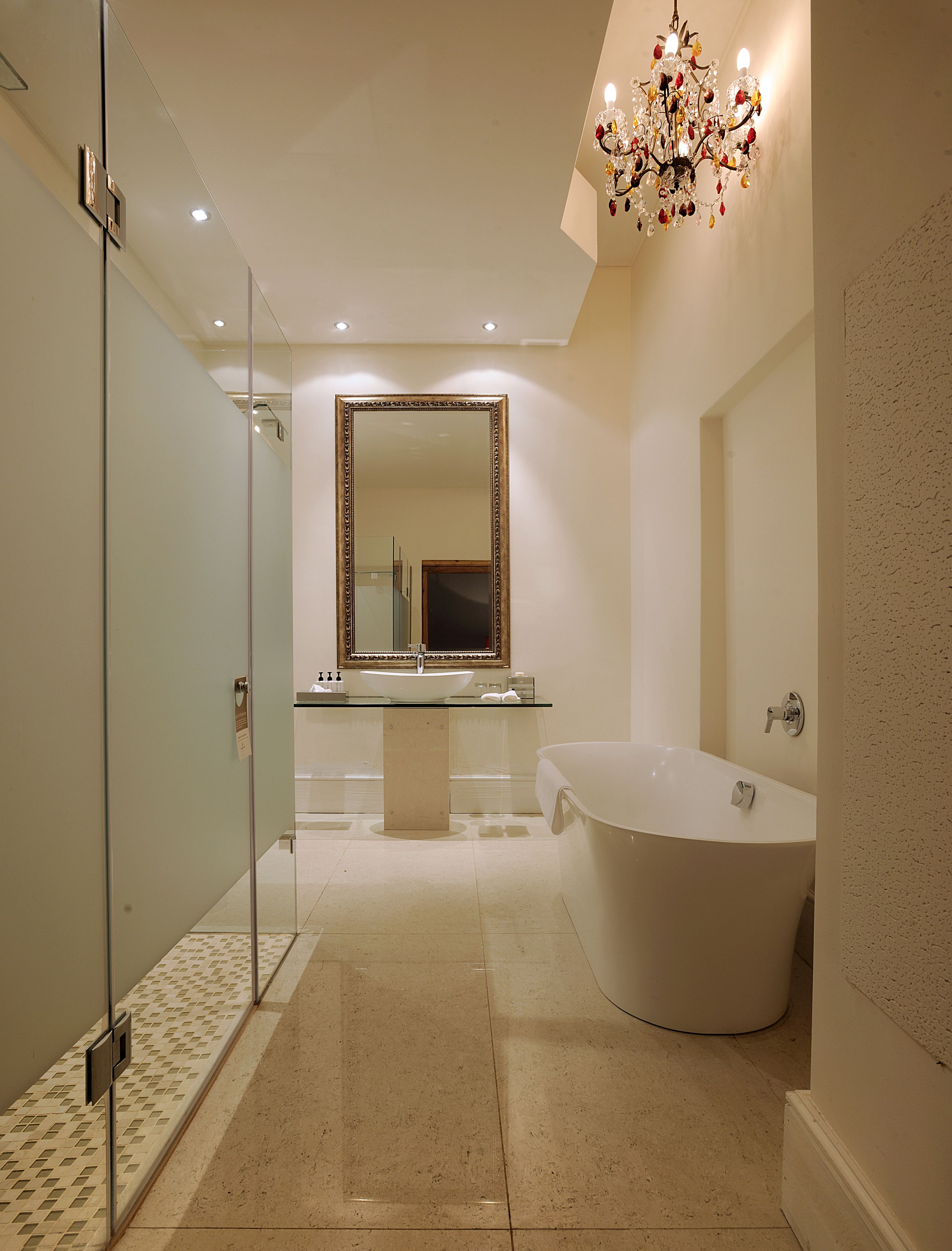 A modern bathroom with a freestanding bathtub, a large mirror, and a chandelier.