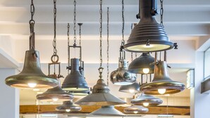 A breakfast buffet with various food items and drinks, a wooden table with a cross design, and hanging industrial-style pendant lights. - Oude Werf Hotel (Stellenbosch)