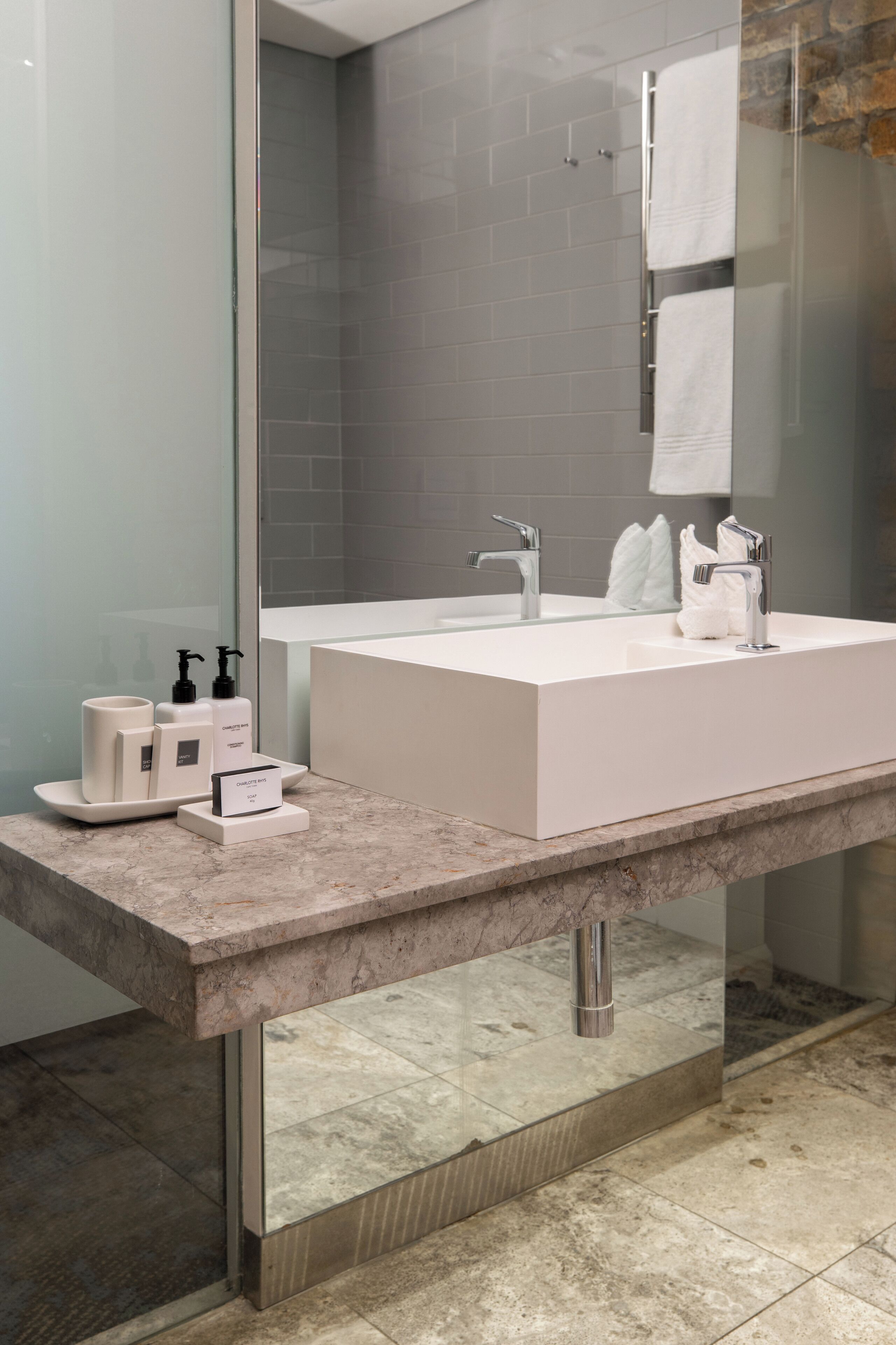 Un baño moderno con un lavabo grande blanco, un cerramiento de ducha de vidrio y una encimera de mármol.