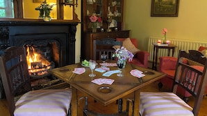 Een gezellige kamer met een open haard, een eettafel gedekt voor twee personen en een comfortabele zithoek.