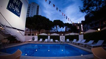 Una piscina al aire libre, sillones reclinables de piscina