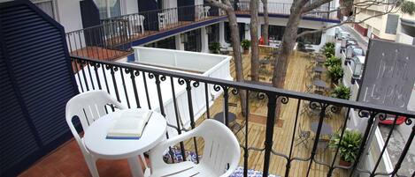 Un balcón con dos sillas de plástico blanco y una pequeña mesa, con vistas a un patio con plantas en macetas y un letrero que dice 'Hotel El Espin'.