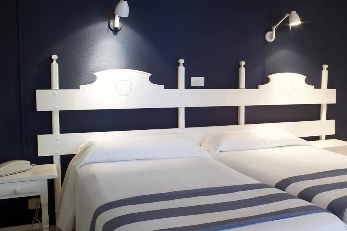 Ein Doppelbett mit weißem Kopfteil und zwei Nachttischlampen.