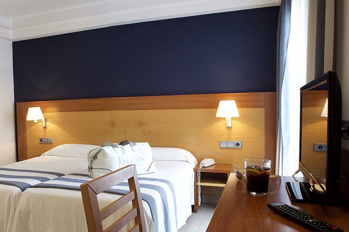 Ein Hotelzimmer mit einem Bett, Nachttischen, Lampen, einem Fernseher und einem Sessel.