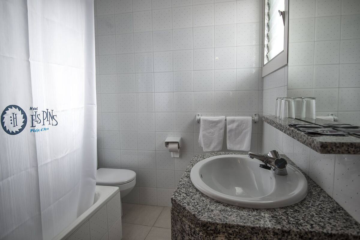 Ein Badezimmer mit Toilette, Waschbecken mit Granitplatte und Duschvorhang.