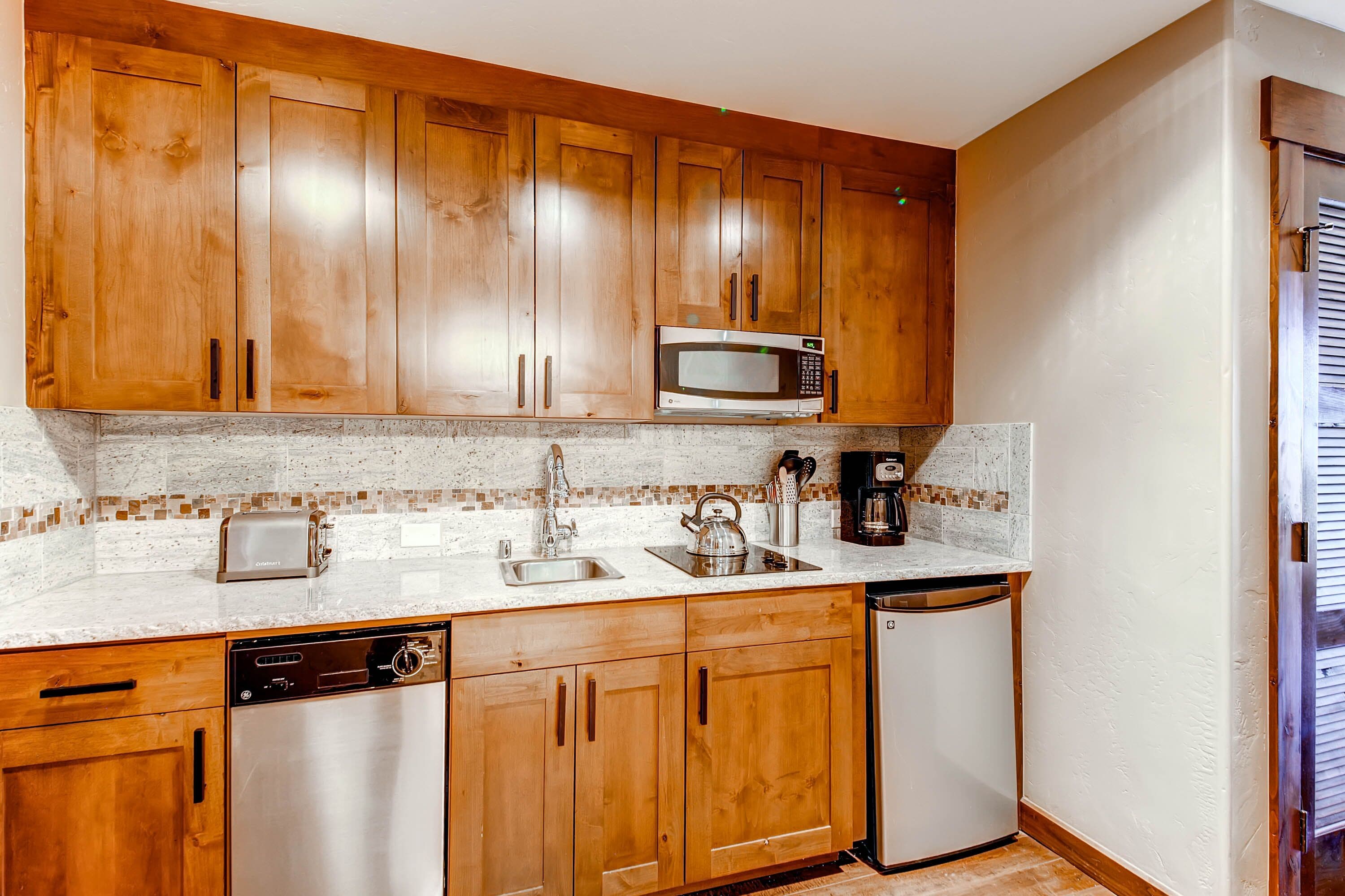 A kitchen with wooden cabinets, a microwave, a toaster, a coffee maker, and a dishwasher.