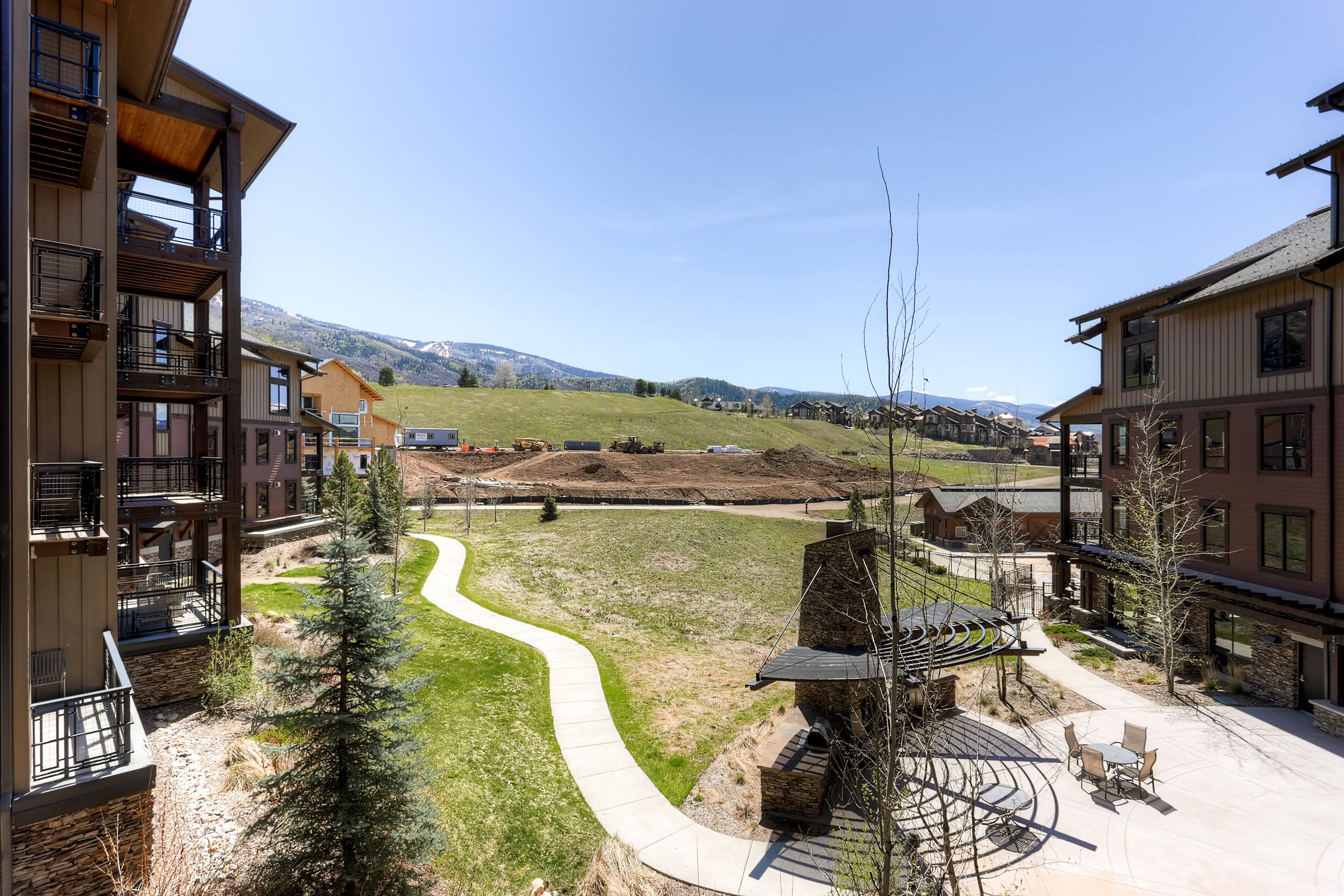 Un quartier résidentiel avec des immeubles à plusieurs étages, un sentier sinueux et une vue sur les montagnes lointaines.