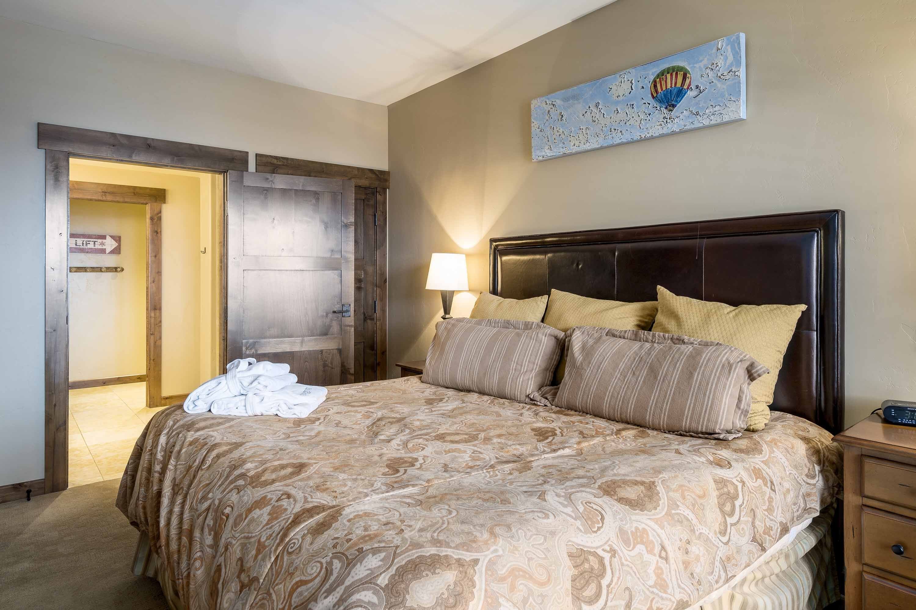 Une chambre à coucher avec un lit, une table de chevet, une lampe, un tableau et une porte avec une pancarte.