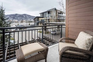 A balcony with wicker furniture and a view of a mountain and buildings.