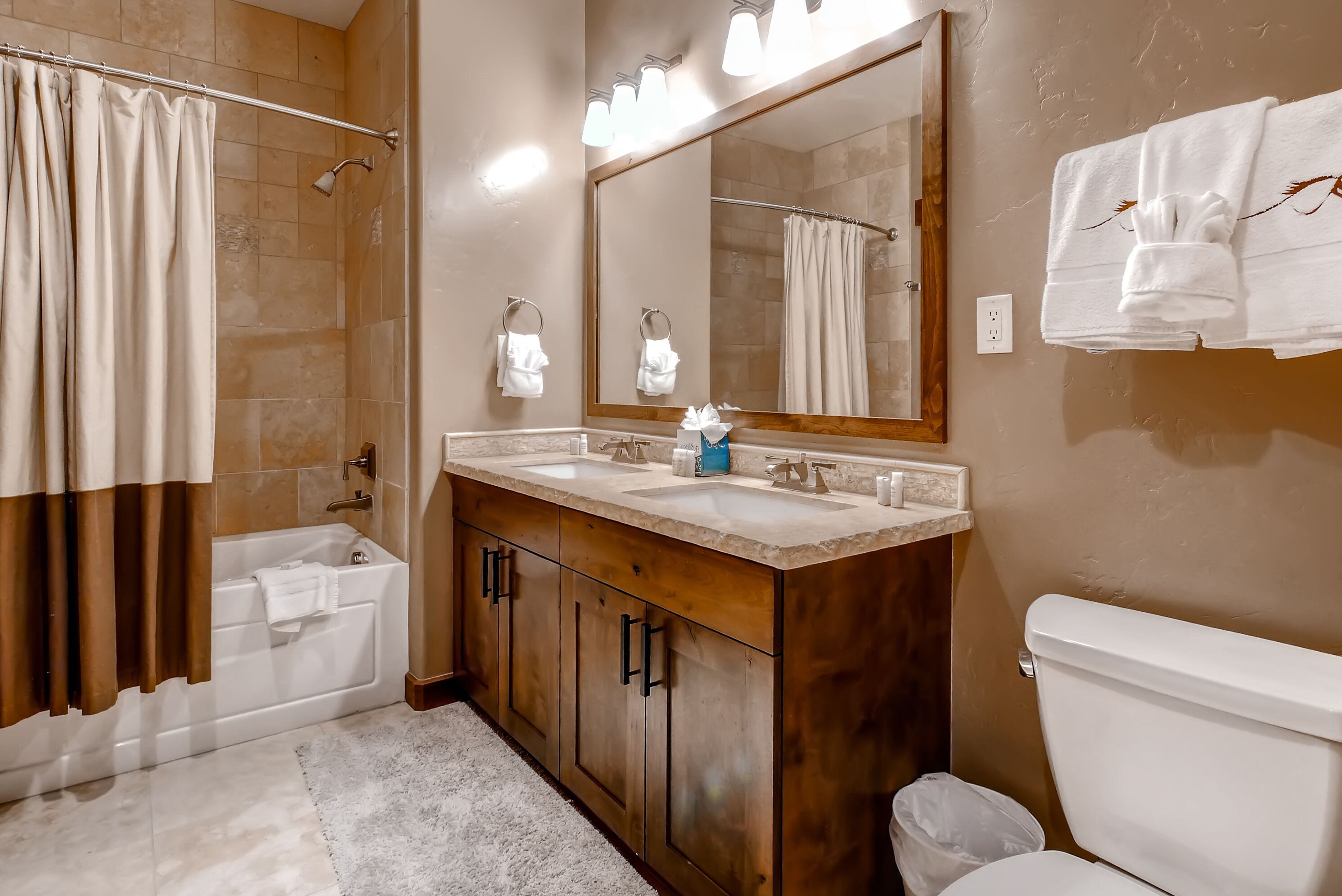 A bathroom with a bathtub, a shower, a toilet, a vanity with a mirror, and a towel rack.