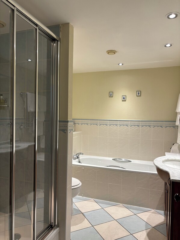Un baño con cabina de ducha de vidrio, bañera, lavabo e inodoro.
