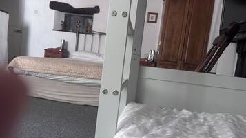 Um quarto com cama de solteiro e beliche, mesa de cabeceira, espelho e guarda-roupa.