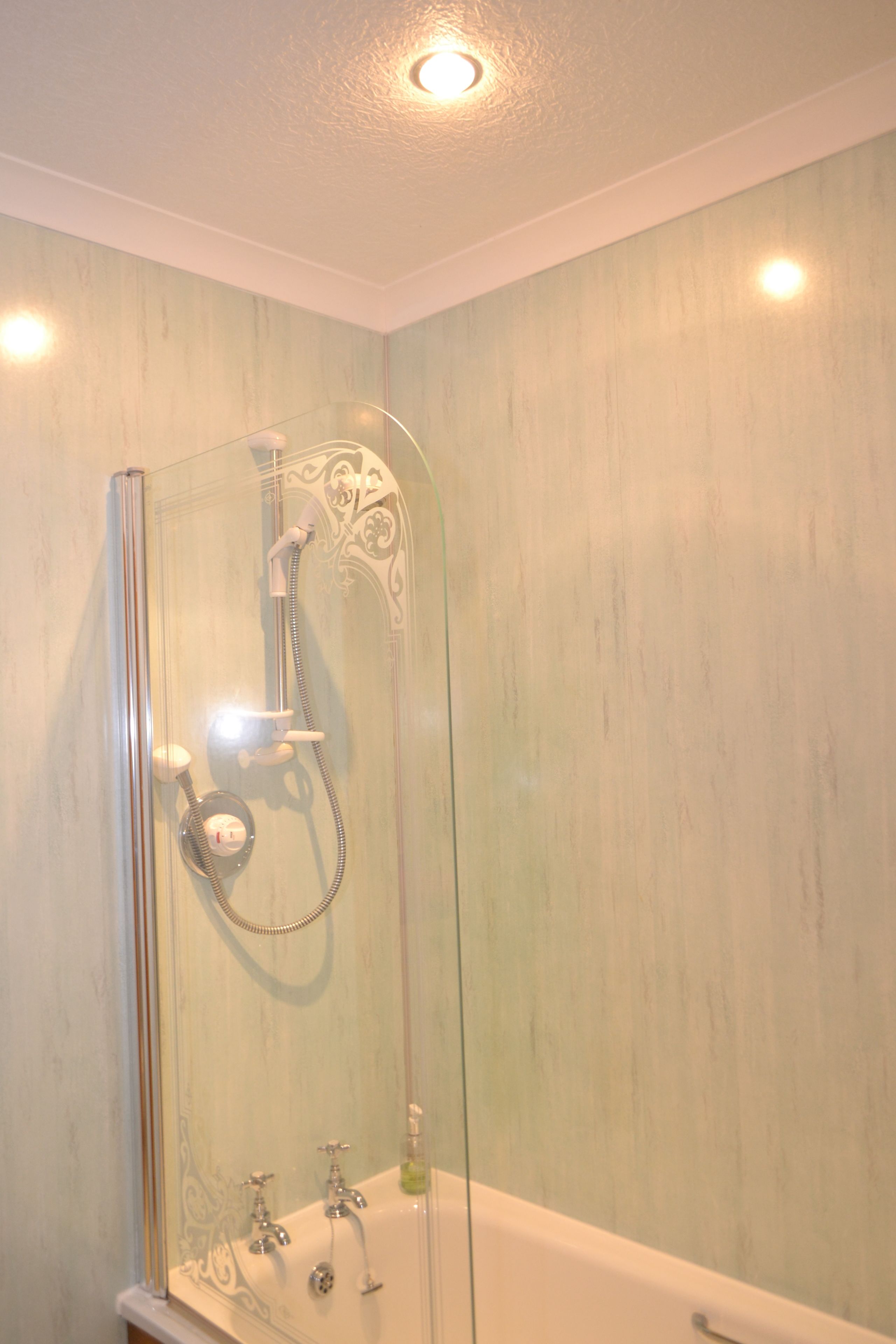 A glass-enclosed shower with a handheld showerhead and a handheld faucet.