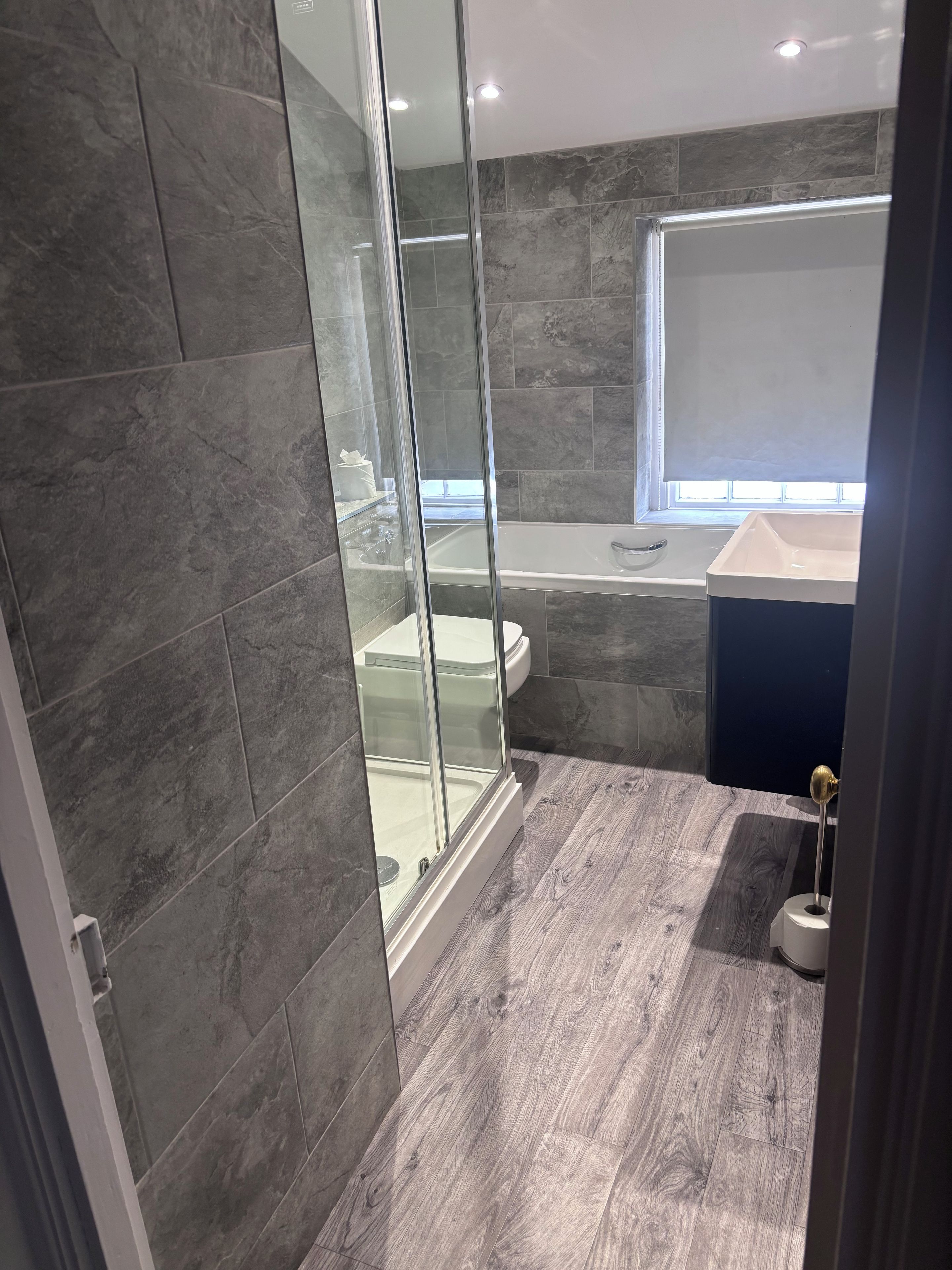 Un bagno moderno con cabina doccia in vetro, una vasca da bagno e un mobile lavabo.