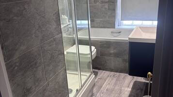 Un bagno moderno con cabina doccia in vetro, una vasca da bagno e un mobile lavabo.