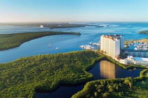 Ein Hotel an der Küste mit einem Hafenbecken, umgeben von Wasser und Grünflächen.