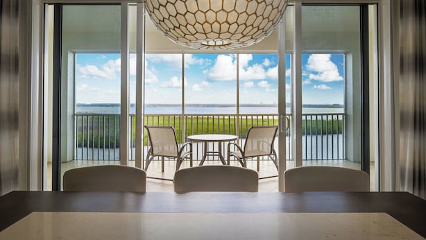 A balcony with a table and chairs, large windows, and a view of the sea. - The Westin Cape Coral Resort At Marina Village (Cape Coral)