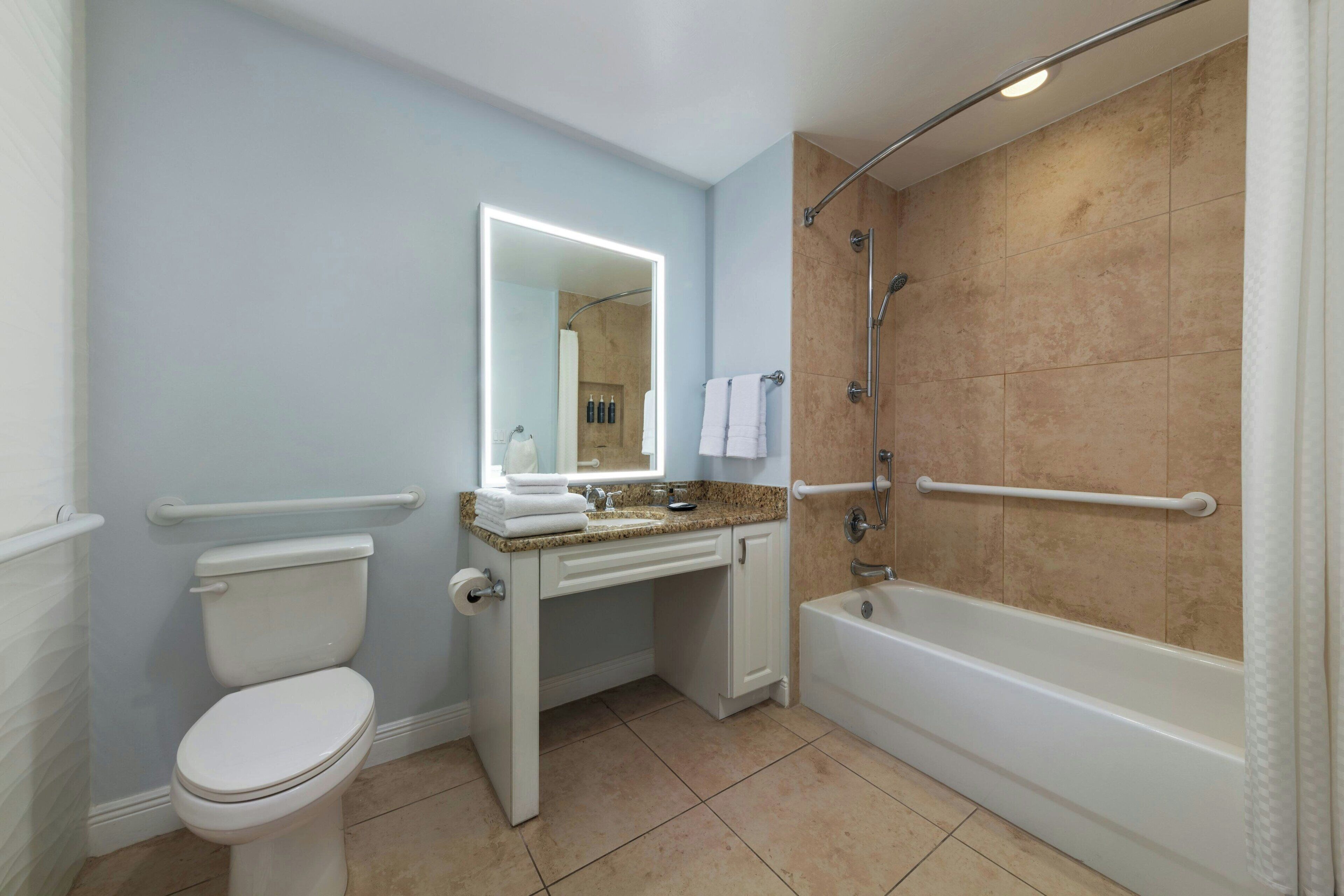 A bathroom with a toilet, sink, mirror, and bathtub.
