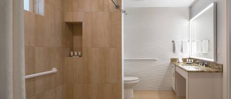 Un baño moderno con ducha, inodoro y tocador.