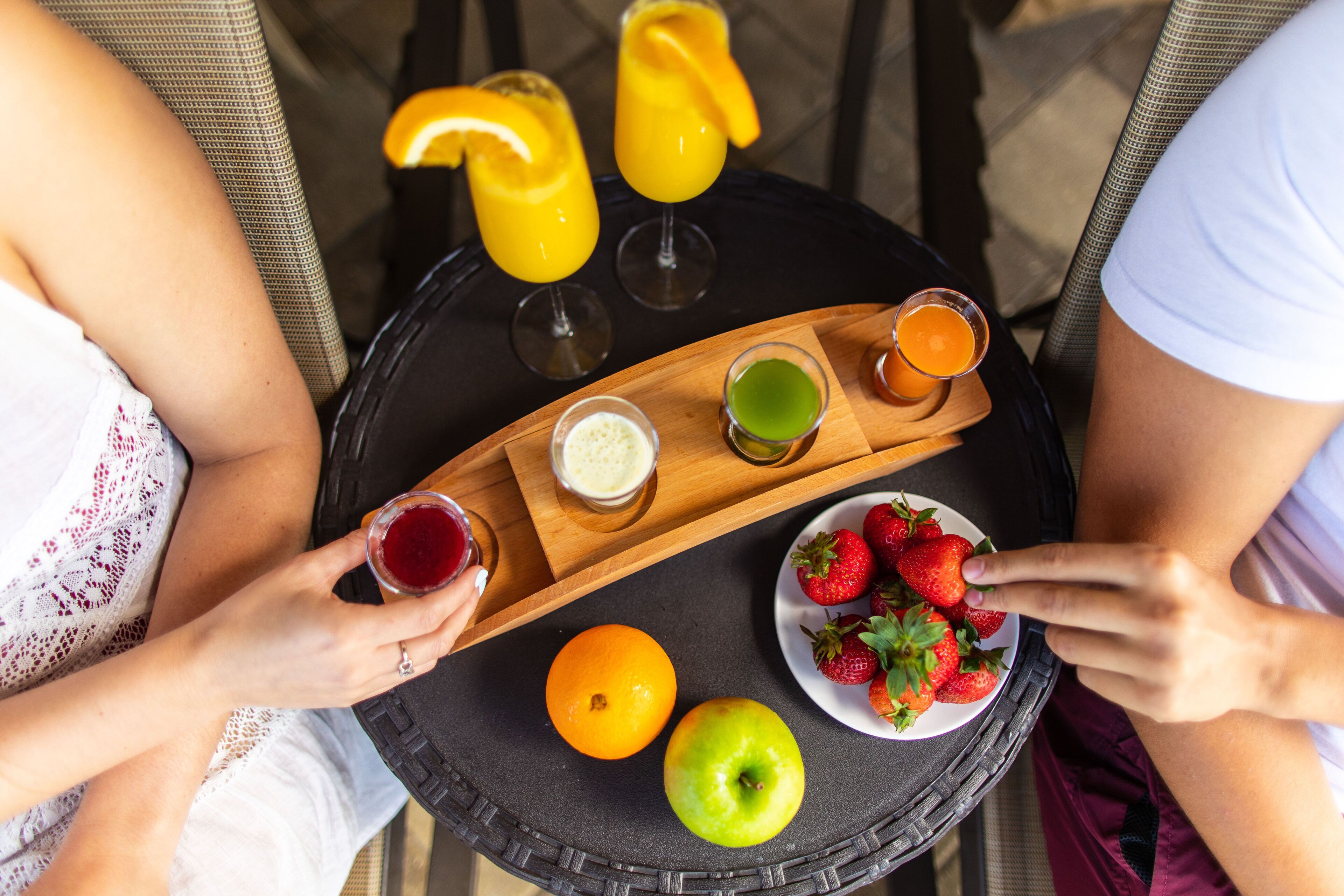 A round table with a tray holding various drinks and fresh fruits.