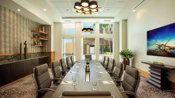 Une salle de conférence avec une longue table, plusieurs chaises, une cafetière et un tableau accroché au mur.
