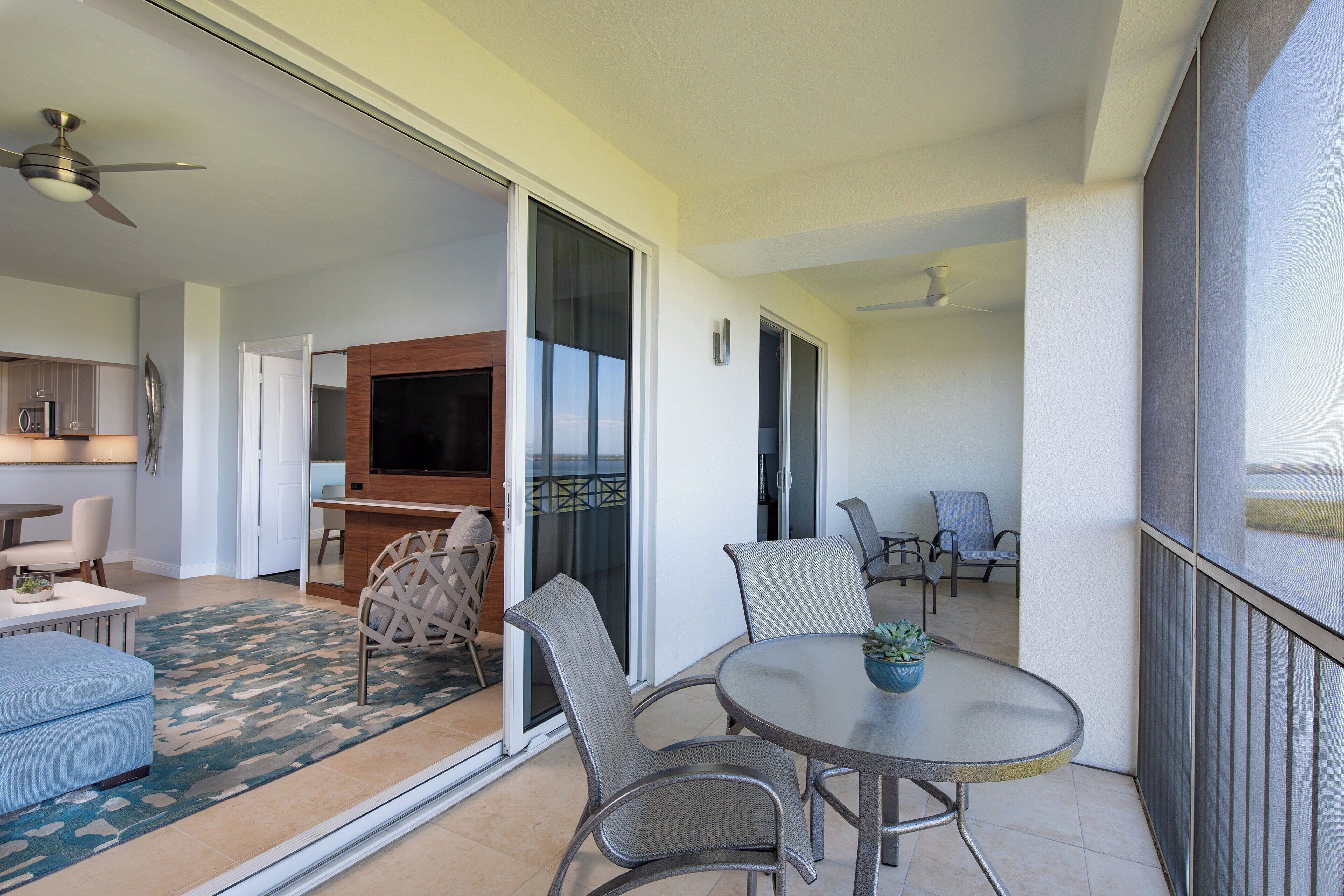 A modern living area with a dining table, chairs, a sofa, and a kitchen area with a TV.