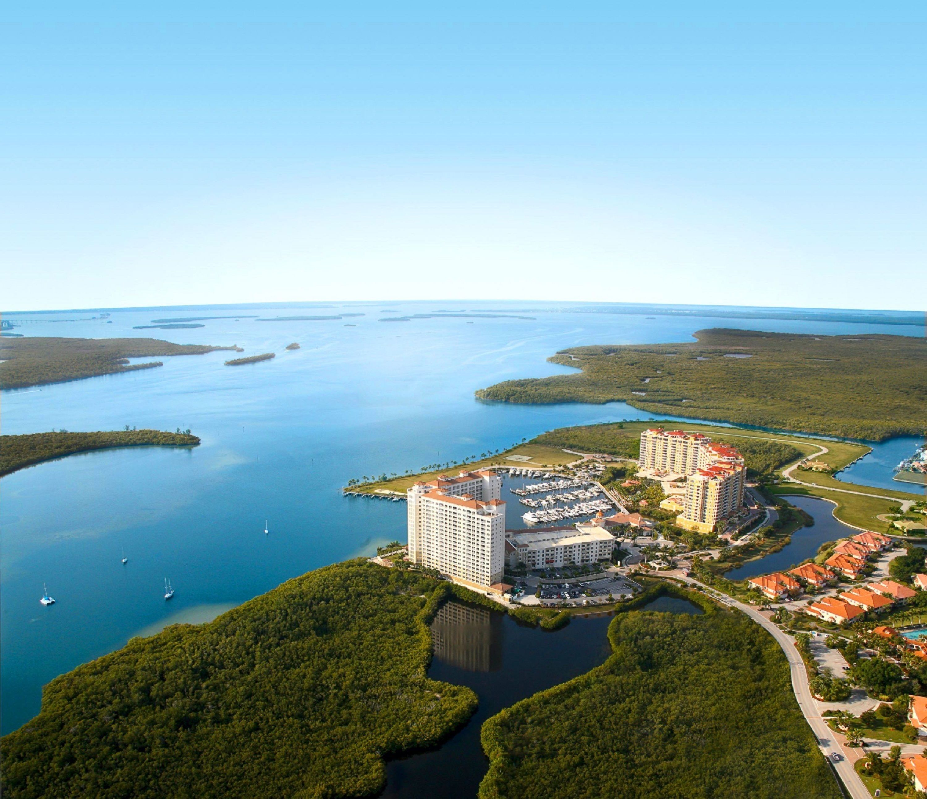 Un hotel costero con varias edificaciones, un puerto deportivo y cuerpos de agua circundantes.