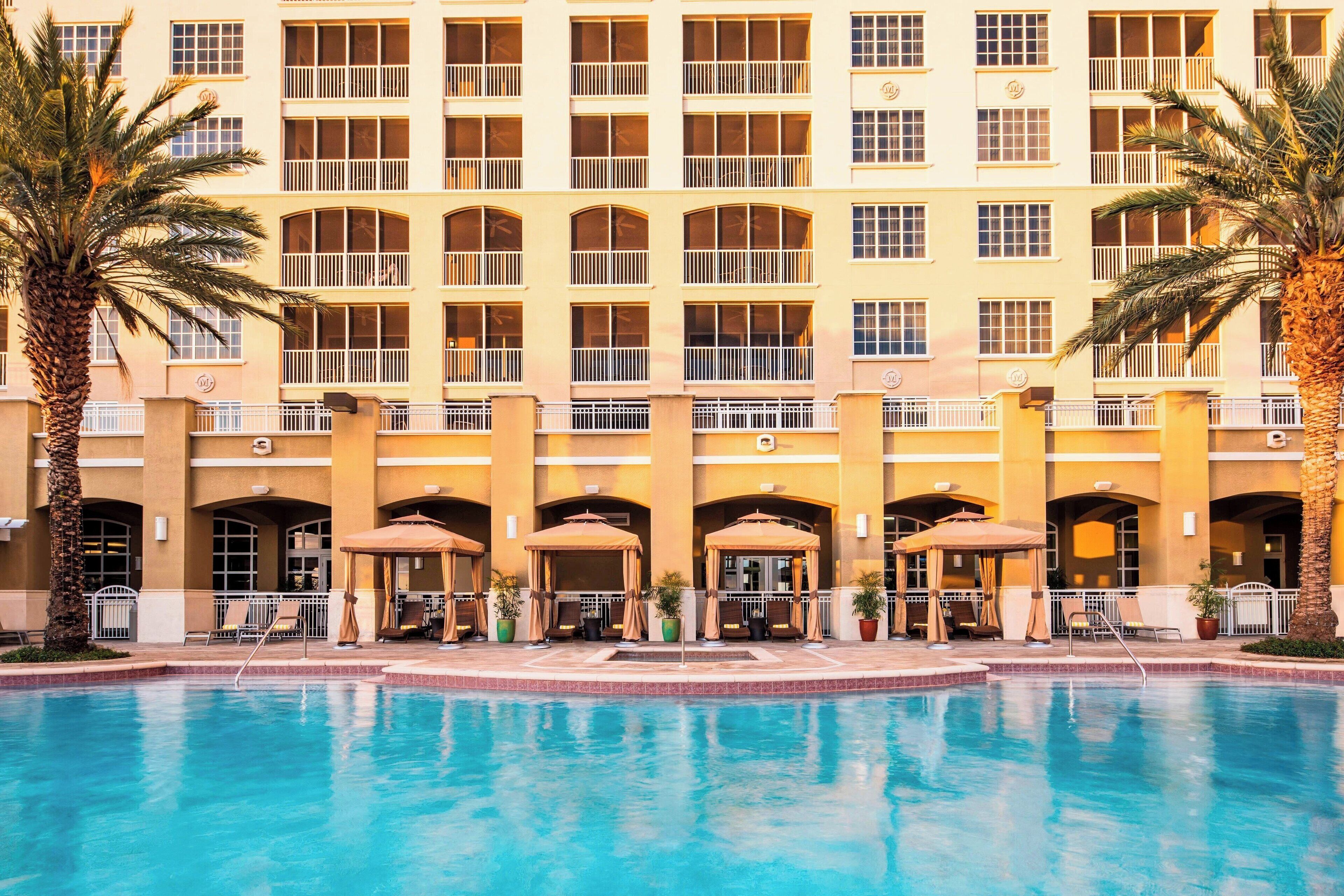 A hotel with a swimming pool, multiple balconies, and outdoor seating areas.