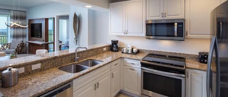 A modern kitchen with granite countertops, stainless steel appliances, and white cabinetry.