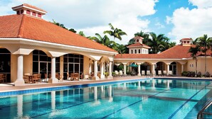 A swimming pool with clear blue water, surrounded by lounge chairs and umbrellas, and a building with a tiled roof. - The Westin Cape Coral Resort At Marina Village (Cape Coral)