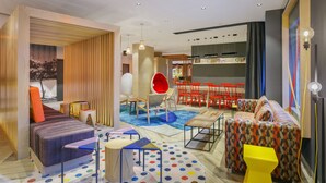 Un interior moderno con un sofá, una butaca roja y una zona de comedor con sillas rojas.