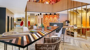 Un comedor moderno con una mesa larga, sillas de mimbre y una decoración de pared llamativa.