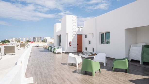 A rooftop terrace with white and green chairs, a wooden door, and a city skyline in the background. - Suites Gaby Cancun (Cancun)