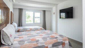 A hotel room with two beds, a flat-screen TV, an air conditioning unit, and a window with curtains. - Suites Gaby Cancun (Cancun)